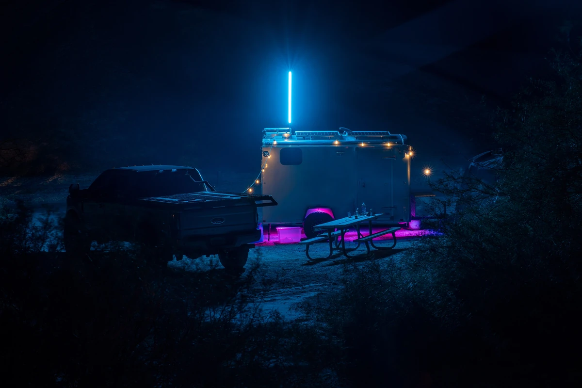 A pickup truck and a small travel trailer lit with string lights at night at Texas Springs Campground in Death Valley