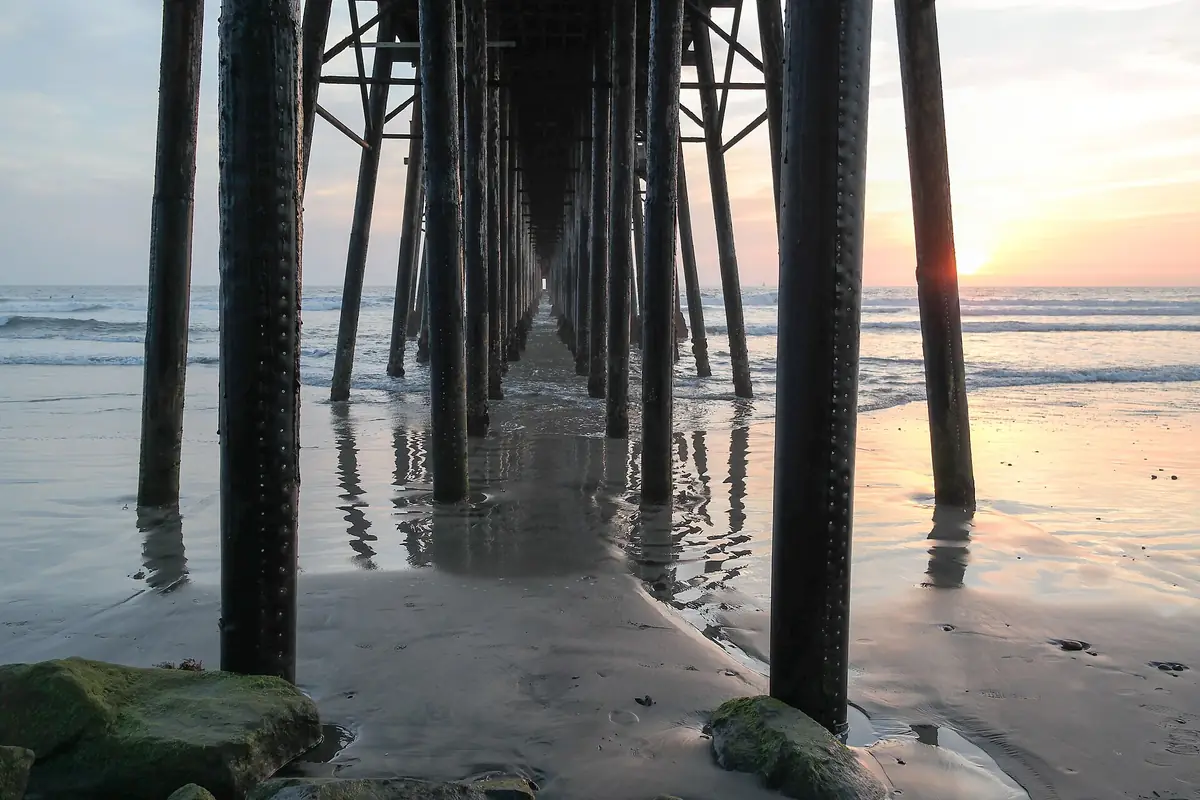 The pilings under the Oceanside Pier at low tide with the sun low